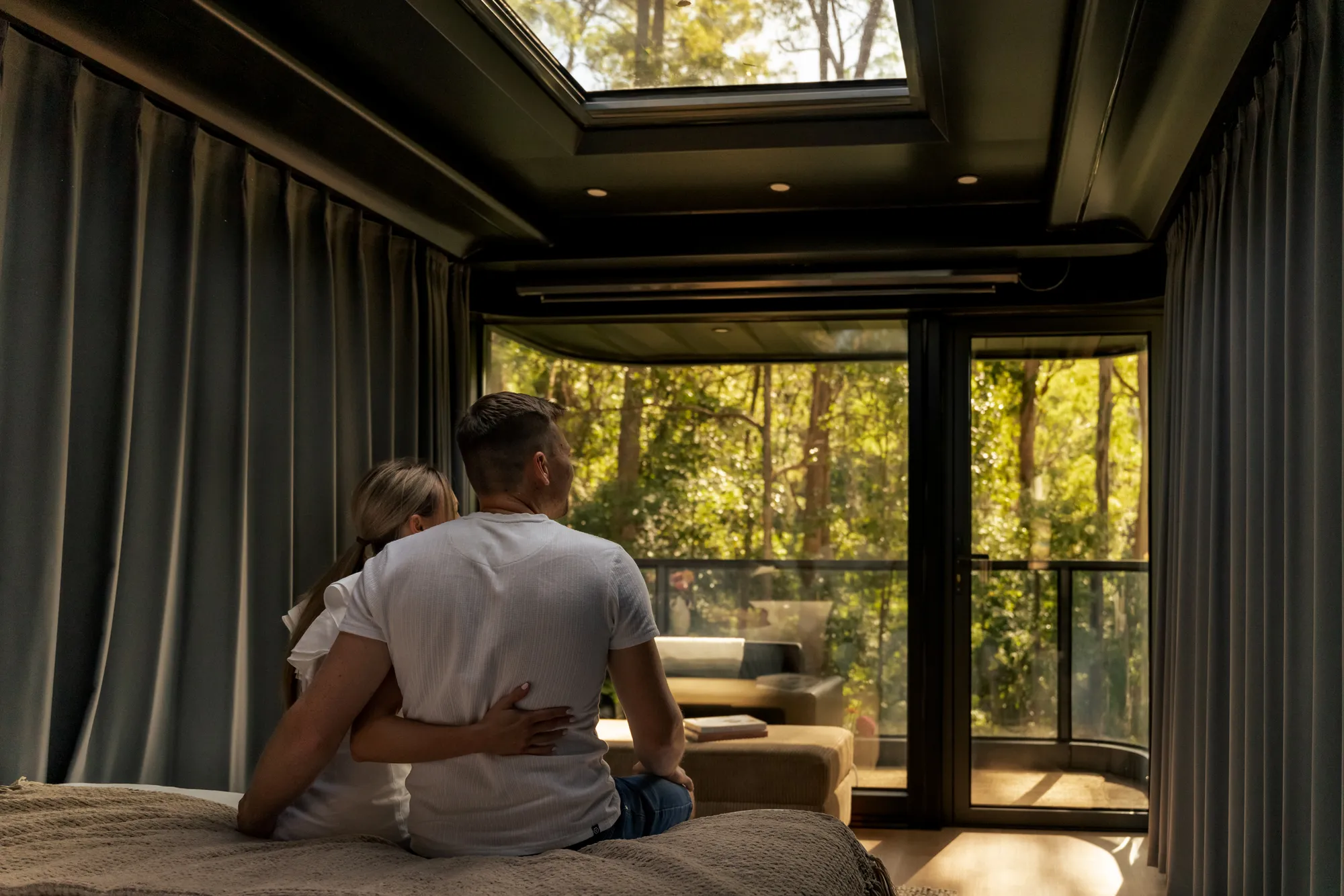 Couple in cabin bedroom looking at forest