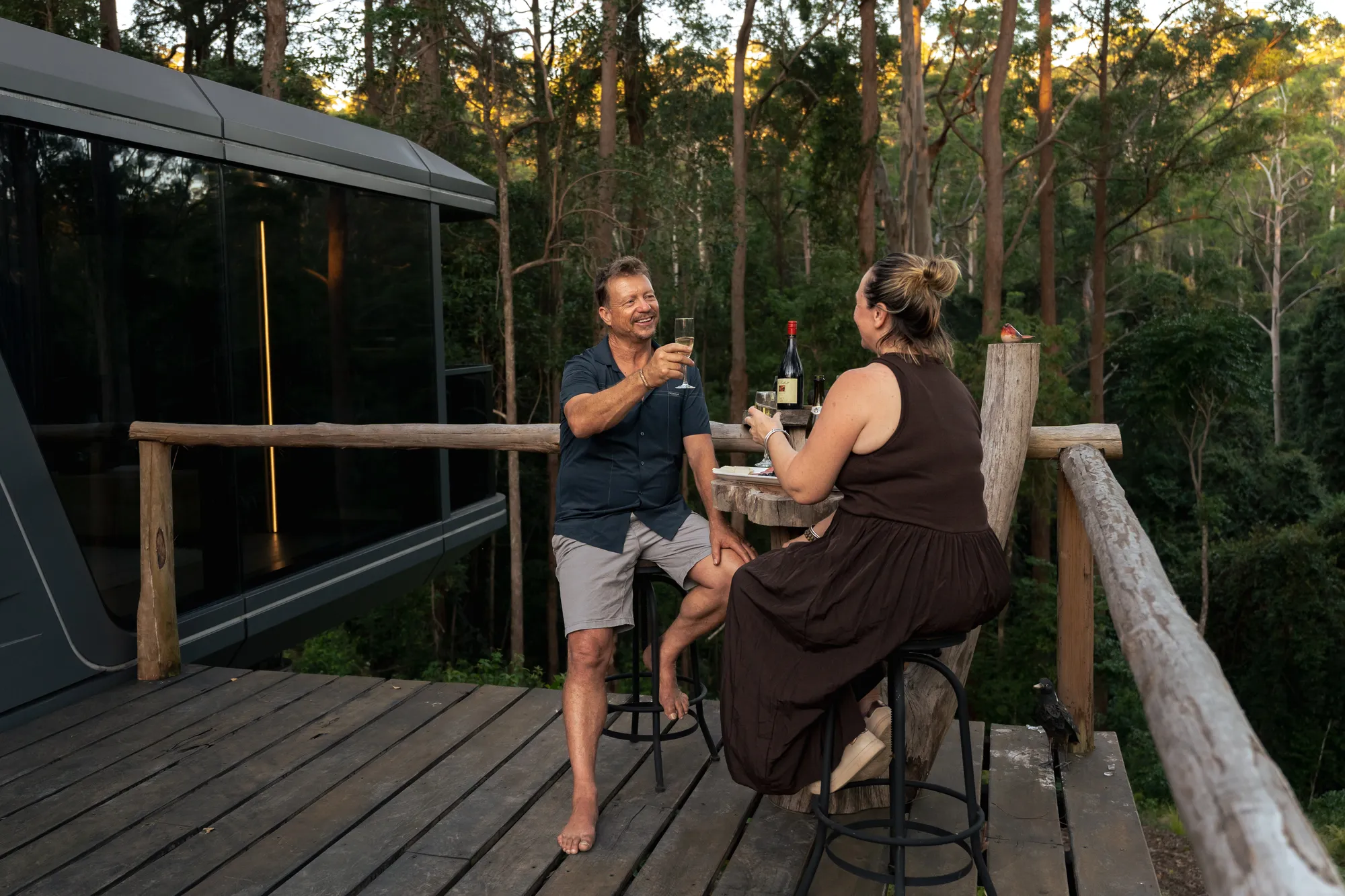 Couple sharing wine on cabin deck at sunset
