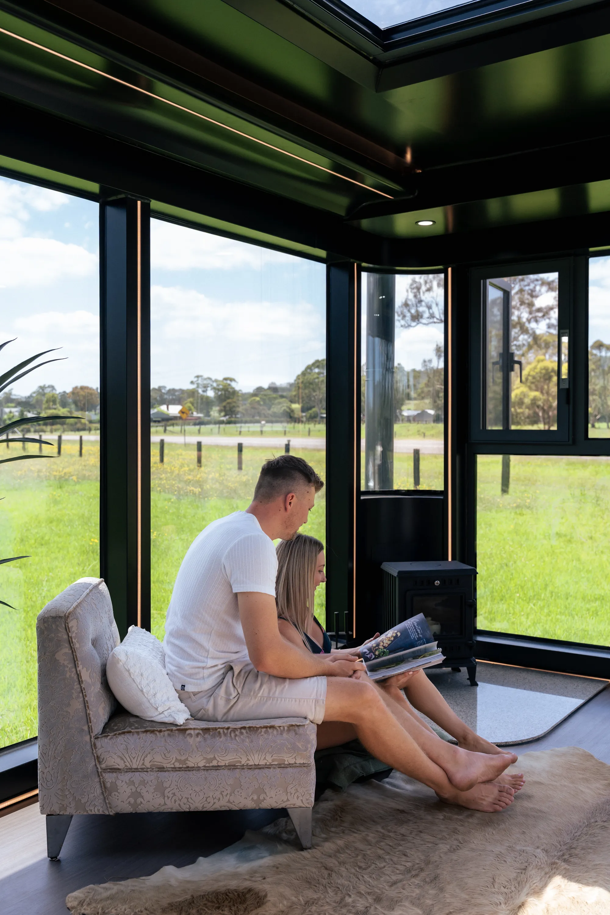 Couple reading inside glass-walled cabin